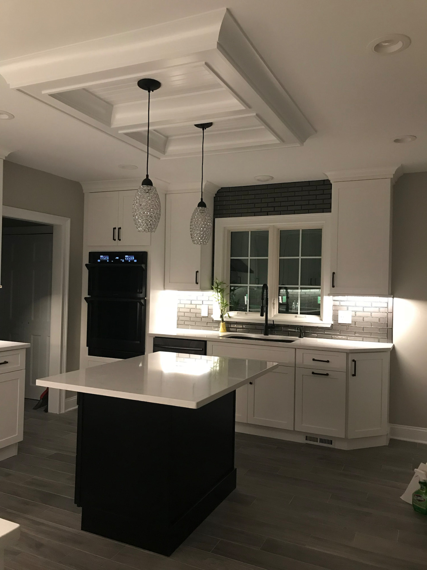 Kitchen remodel with black island, coffered ceiling, and pendant lighting