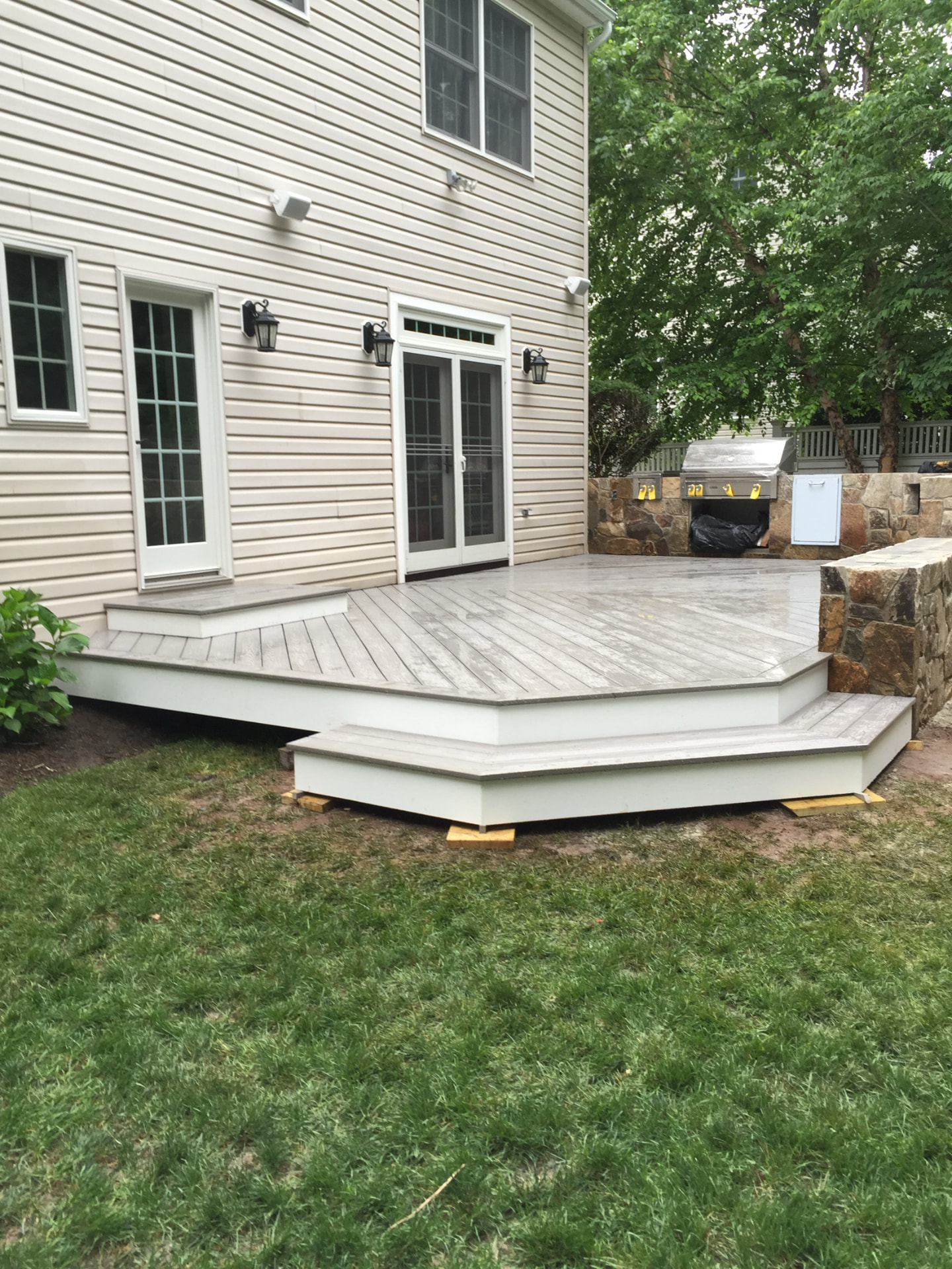 Gray composite deck with stone outdoor kitchen